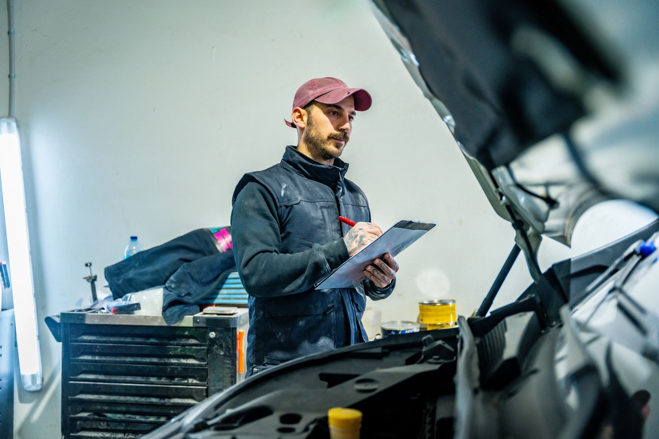 Mechanic inspecting vehicle damage and writing a report